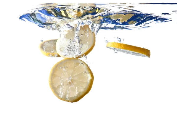 Lemon slices fall into water — Stock Photo, Image