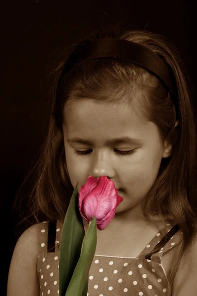 A small girl smelling a flower
