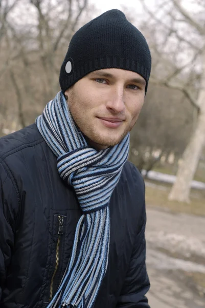 Retrato de un joven con gorra negra y bufanda a rayas — Foto de Stock
