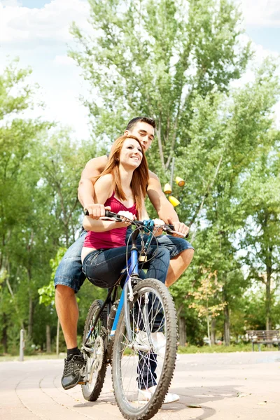 Pareja en una bicicleta sonriendo al aire libre — Foto de Stock