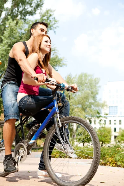 Love couple riding a bicycle in a park — Stock Photo, Image