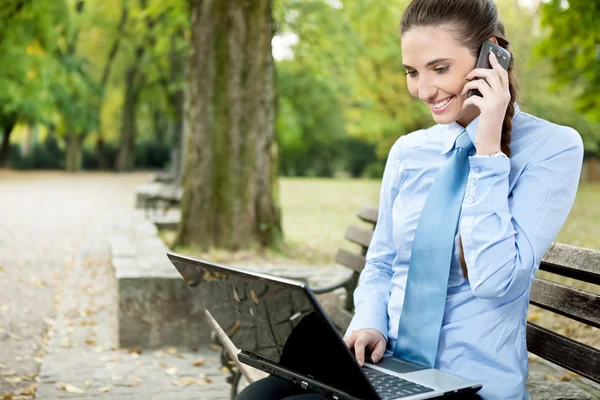 Affärskvinna med telefon och laptop — Stockfoto