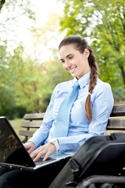 在公园中使用的笔记本电脑的女商人 — 图库照片