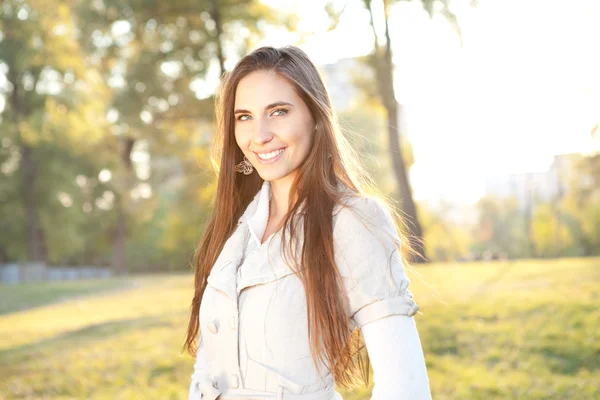 Donna sorridente con parco autunnale sullo sfondo — Foto Stock