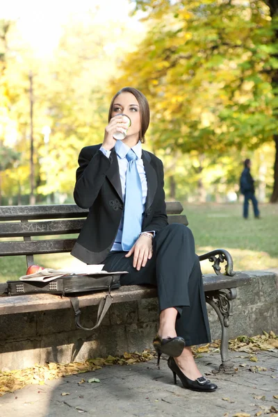 Zakenvrouw in park drinken koffie — Stockfoto