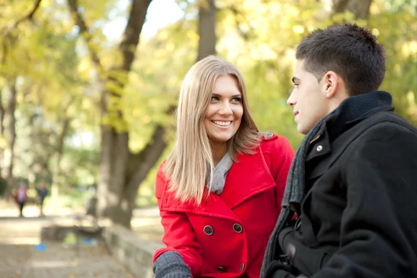 Усміхнена молода пара розмовляє в парку — стокове фото