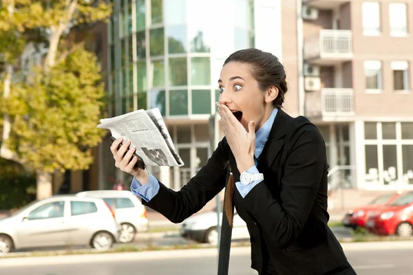 Surprised businesswoman with news in newspaper — Stock Photo, Image