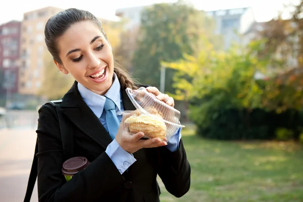 Empresária sorridente comendo um donut — Fotografia de Stock