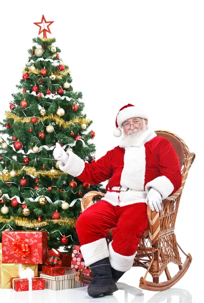 Санта сидит рядом с елкой — стоковое фото