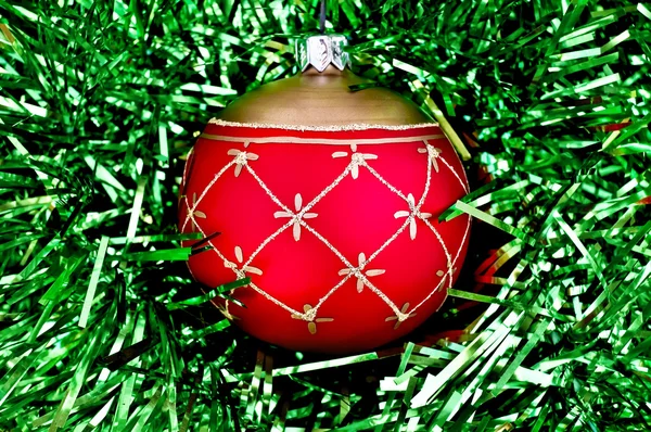 Bola vermelha de Natal no ouropel verde — Fotografia de Stock