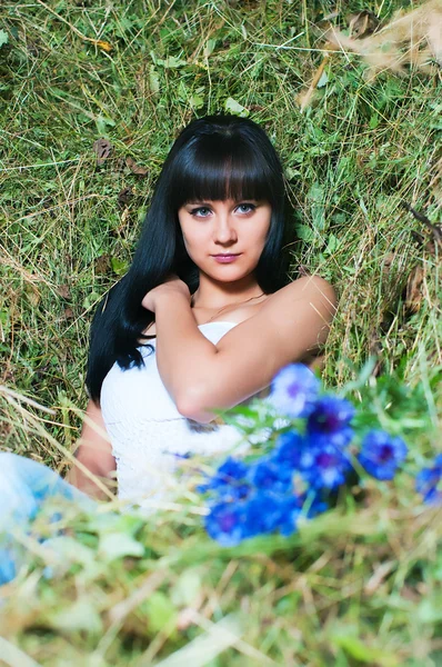 Het meisje op hooi met bloemen — Stockfoto