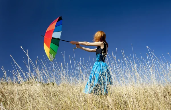 Ruiva menina com guarda-chuva no prado grama ventosa . — Fotografia de Stock