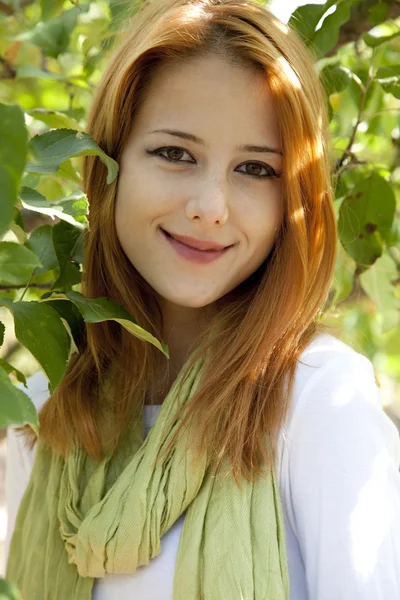 Vackra unga rödhårig kvinna som står nära äppelträdet. — Stockfoto