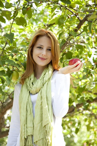 Elma ağacının yanında duran genç güzel kızıl saçlı kadın. — Stok fotoğraf