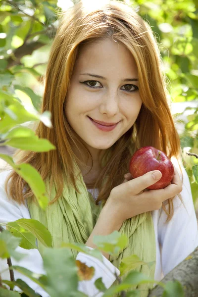Beautiful young redhead woman standing near the apple tree. — Stock Photo, Image