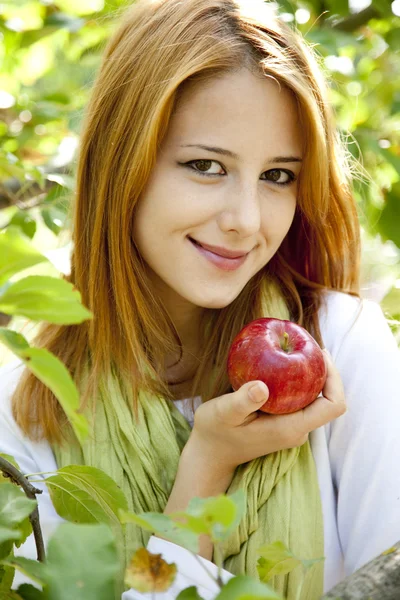 สาวผมแดงสวย ยืนอยู่ใกล้ต้นแอปเปิ้ล . — ภาพถ่ายสต็อก