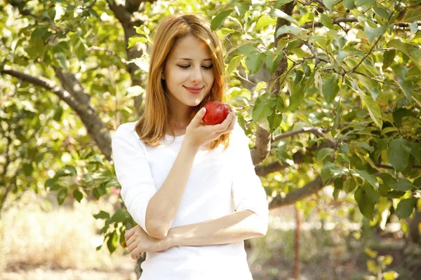 Elma ağacının yanında duran genç güzel kızıl saçlı kadın. — Stok fotoğraf