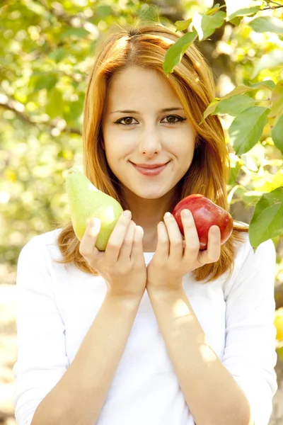 สาวผมแดงสวย ยืนอยู่ใกล้ต้นแอปเปิ้ล . — ภาพถ่ายสต็อก