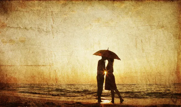 Par kyssar på stranden i solnedgången. — Stockfoto
