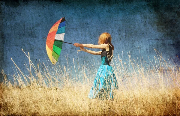 Redhead girl with umbrella at windy grass meadow. — Stock Photo, Image