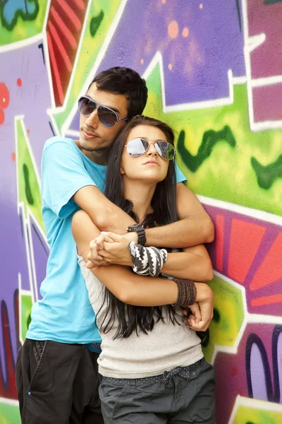 Mladý pár poblíž graffiti pozadí — Stock fotografie