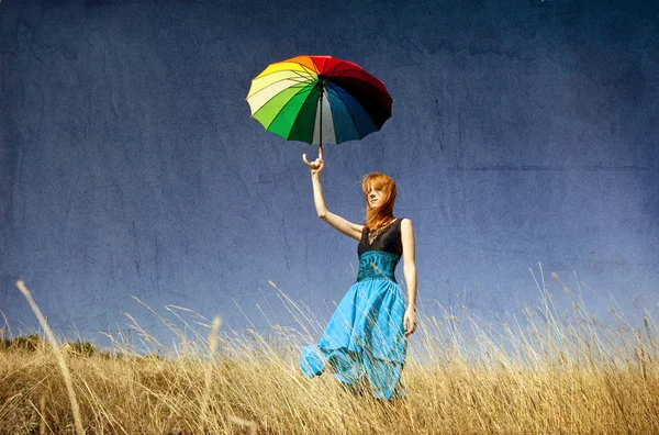 Redhead girl with umbrella at windy grass meadow. — Stock Photo, Image