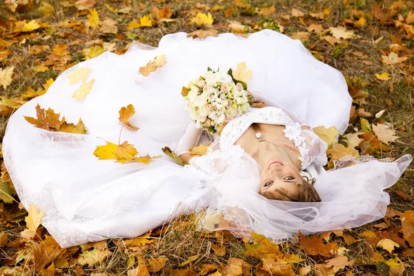 Beautiful bride liying down in the park. — Stock Photo, Image