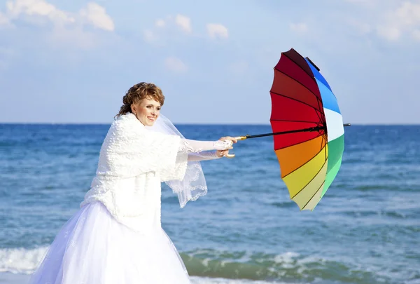 Junge Braut am Strand mit Sonnenschirm. — Stockfoto