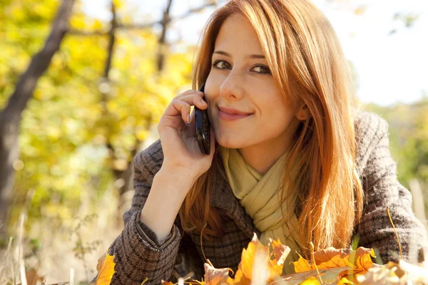 Rödhårig tjej ringer i telefonen i höst park. — Stockfoto