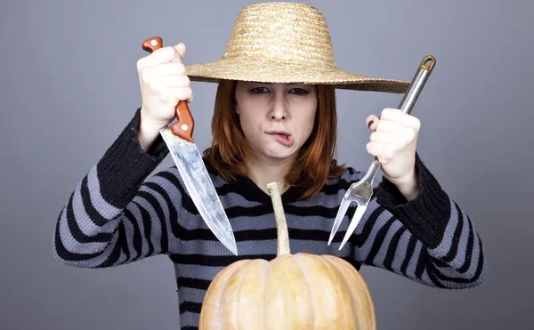 Funny girl in cap and fork with knife try to eat a pumpkin. — Stock Photo, Image