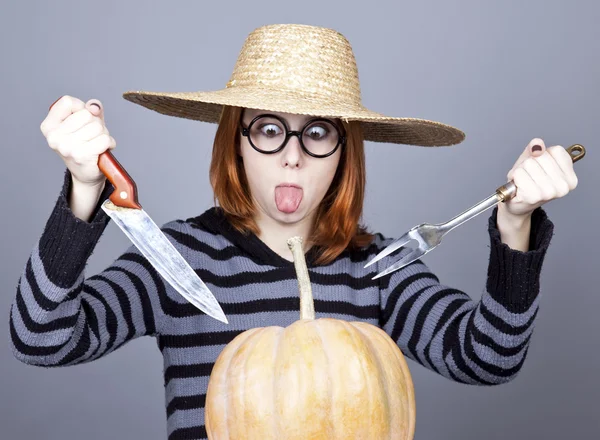 Menina engraçada em boné e garfo com faca tentar comer uma abóbora . — Fotografia de Stock