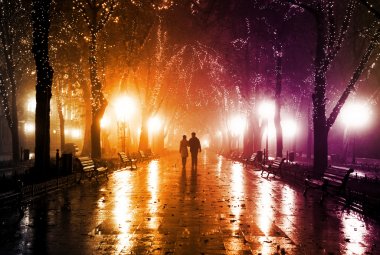 Çift, gece ışıkları sokakta yürürken.