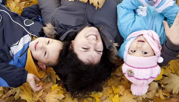 Madre y sus hijos están jugando en el parque de otoño — Foto de Stock