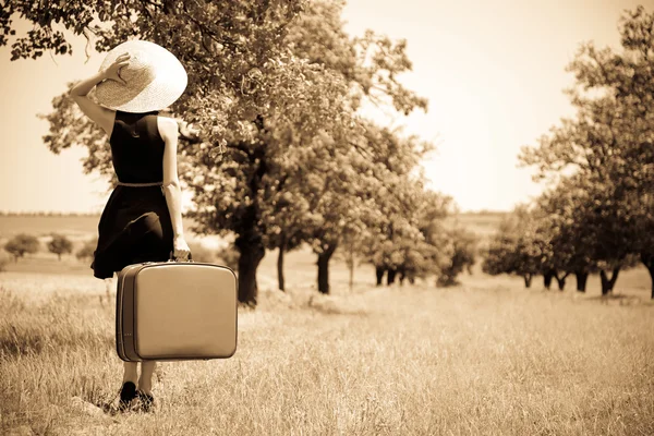 Одинокая девушка с чемоданом в деревне — стоковое фото