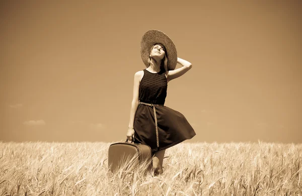 Girl with suitcase at summer wheat field. — Stock Photo, Image