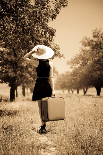Одинокая девушка с чемоданом в деревне — стоковое фото