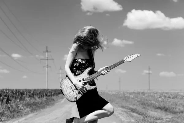 Skała dziewczyna z gitara w okolicy. — Zdjęcie stockowe
