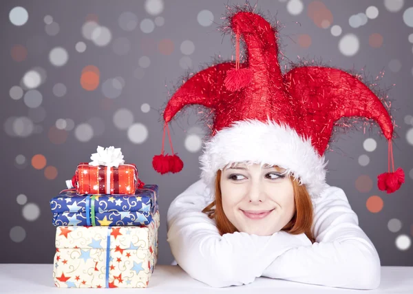 Funny red-haired girl in christmas cap with gift boxes. — Stock Photo, Image