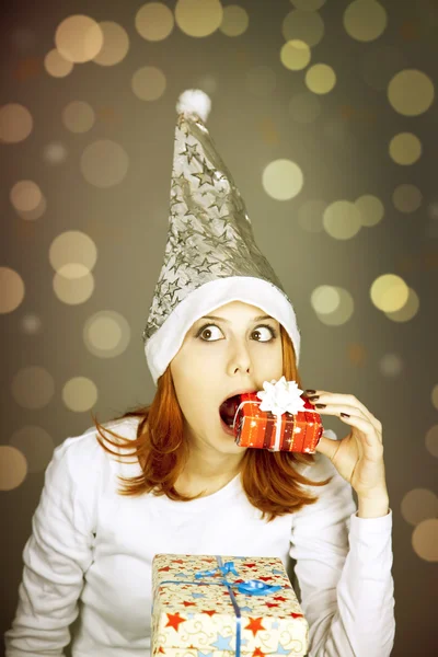 Chica pelirroja divertida en gorra de Navidad con cajas de regalo . —  Fotos de Stock