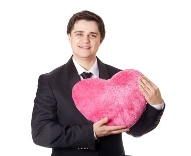 A man holding toy heart in formal black tux with tie isolated on