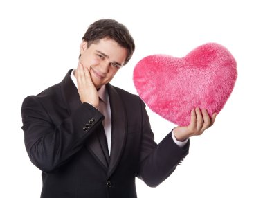 A man holding toy heart in formal black tux with tie isolated on