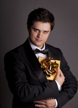 A man holding present box in formal black tux