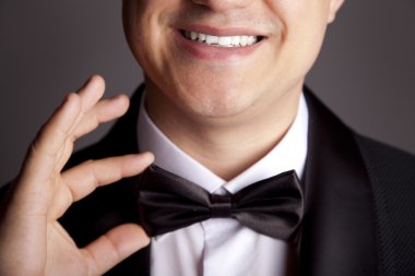 A close-up shot of a man straightening his tux.