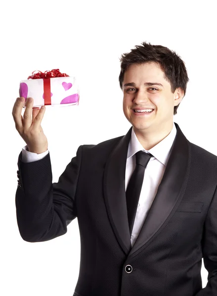 Un uomo con in mano una scatola regalo in smoking nero formale — Foto Stock
