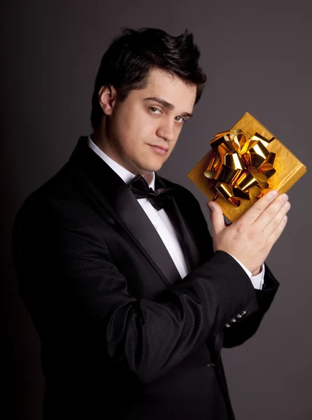 Um homem segurando caixa presente em smoking preto formal — Fotografia de Stock