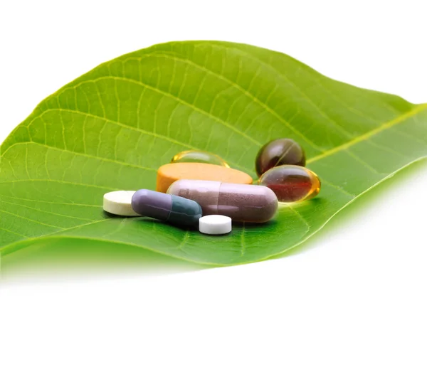 Vitamins, tablets and pills on green leaf — Stock Photo, Image