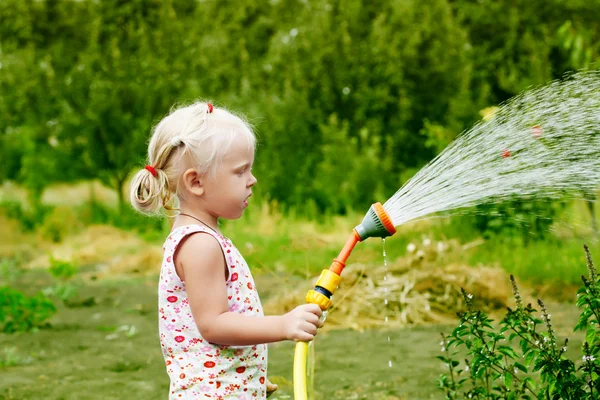 Bahçedeki çimleri sulayan küçük kız — Stok fotoğraf