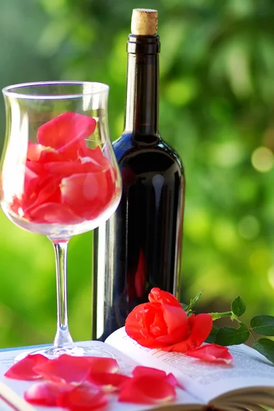 Blütenblätter der roten Rose im Glas Wein. — Stockfoto