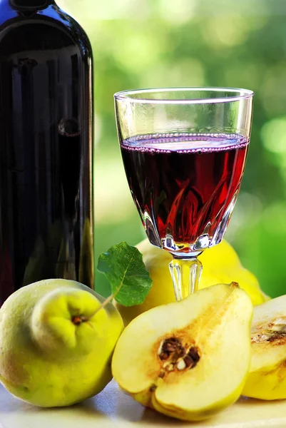 Glass of red wine and quince fruits. — Stock Photo, Image