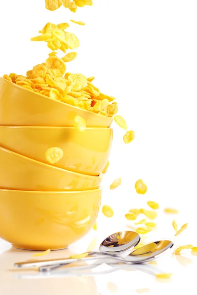 Pila de cuencos amarillos y copos de maíz de oro cae en el tazón — Foto de Stock